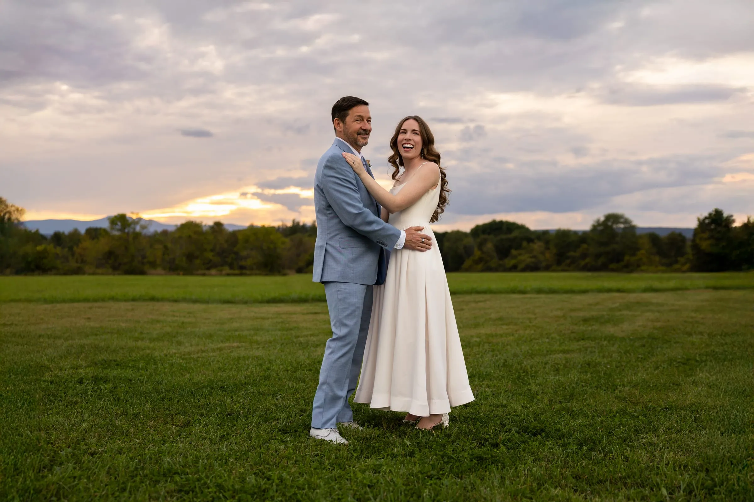 Couple embracing in a wide green field at sunset