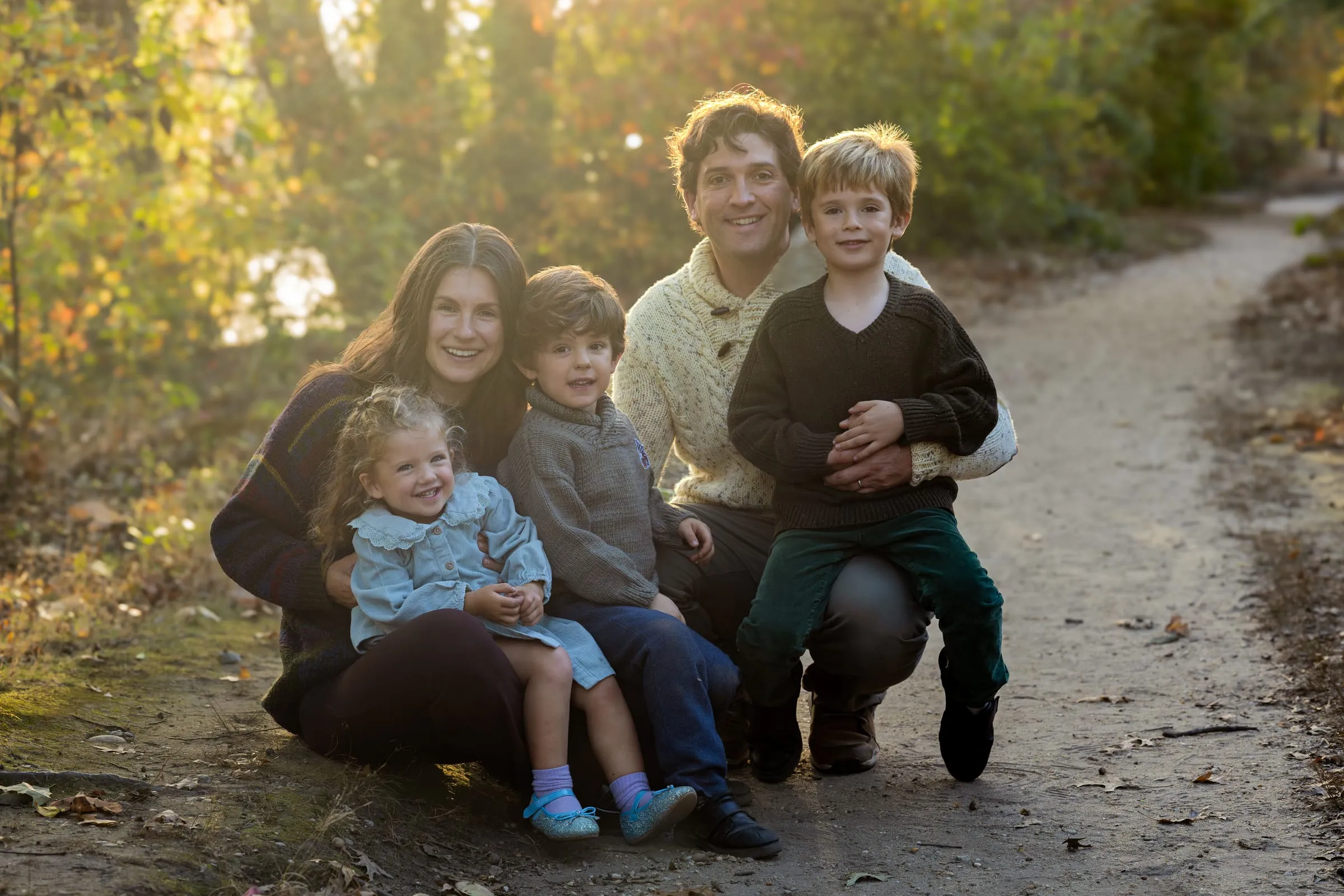 Family of five sitting together on a trail