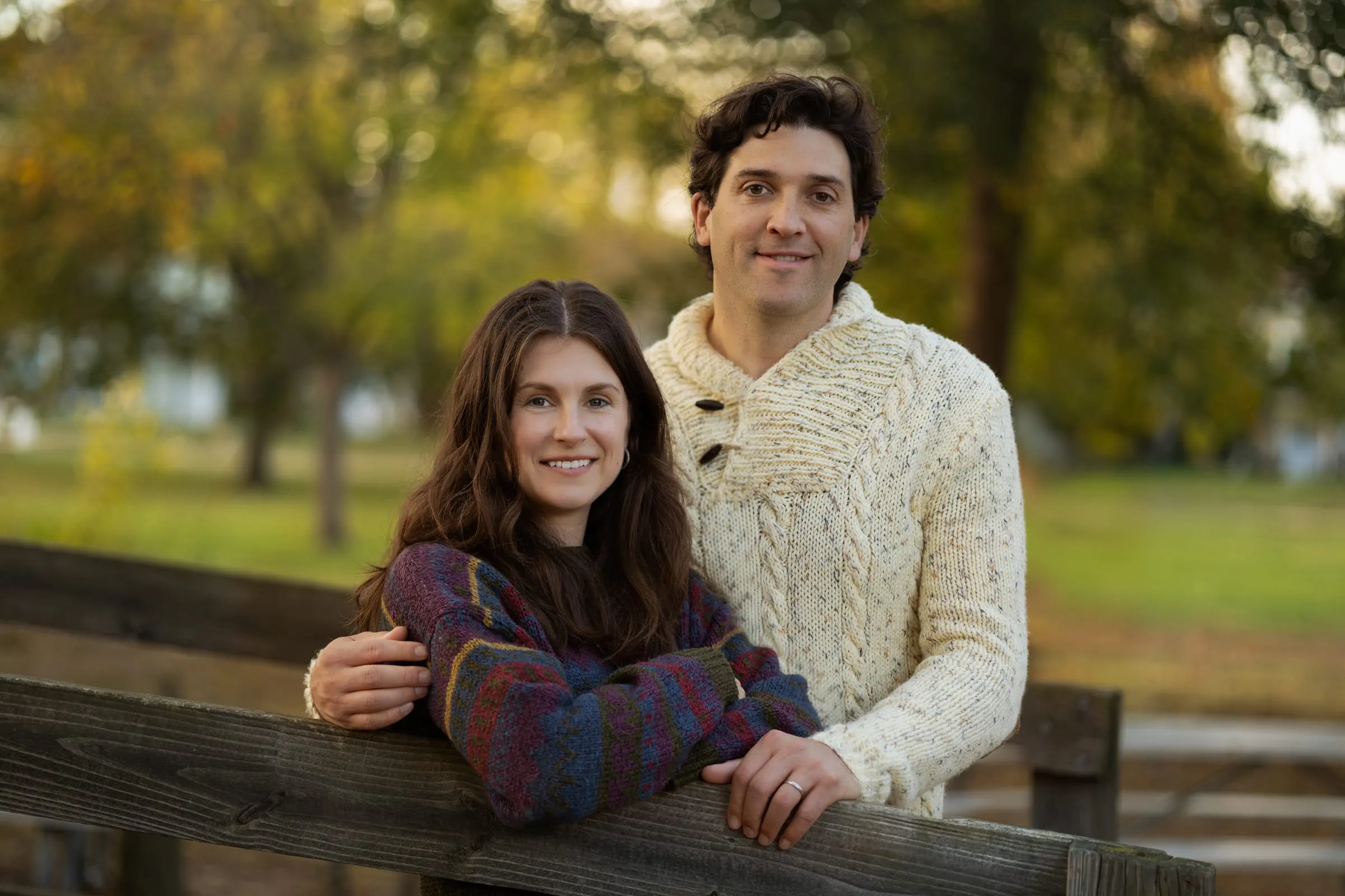 Parents leaning on a wooden bridge railing