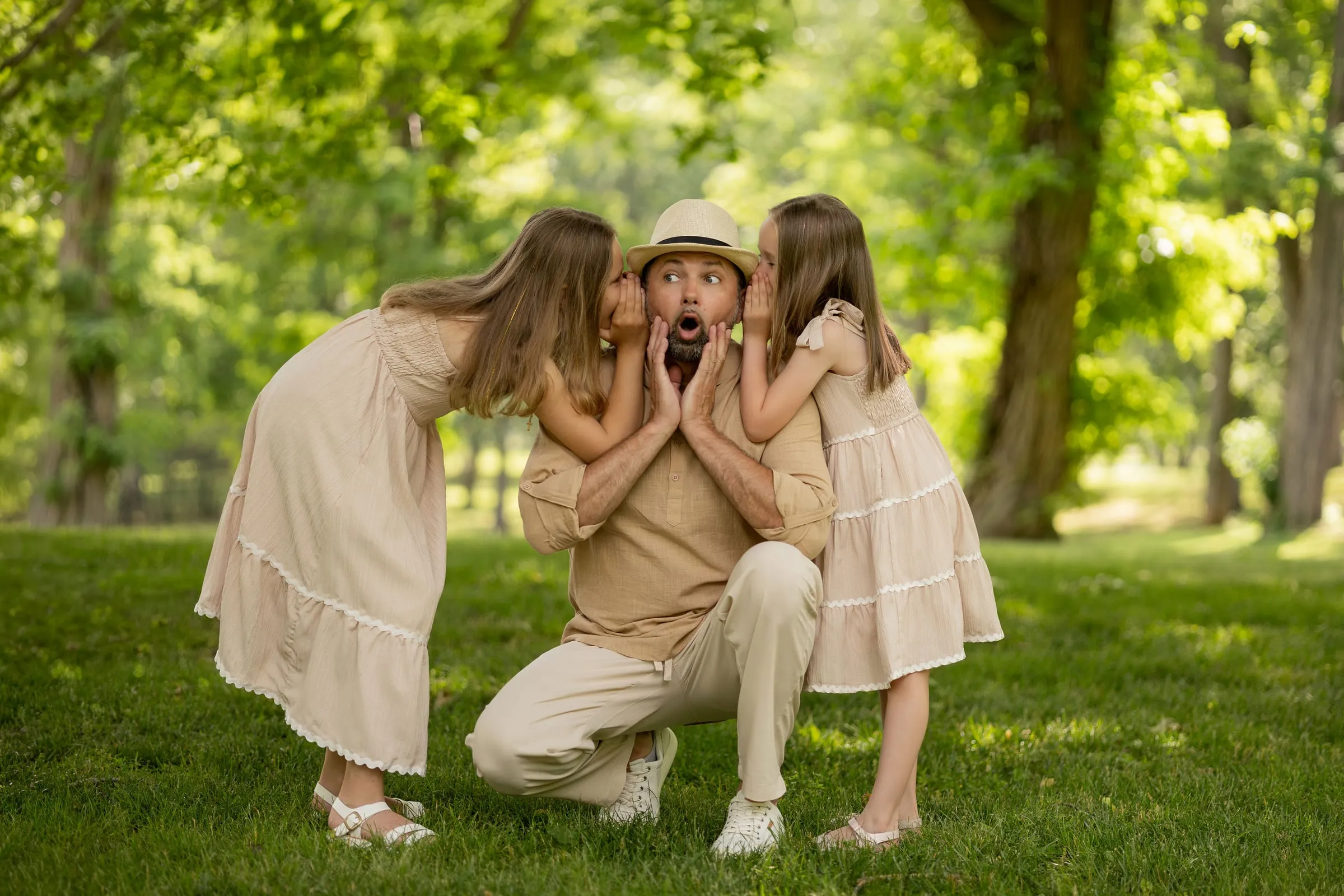 Daughters whispering into their dad’s ears as he makes a surprised face