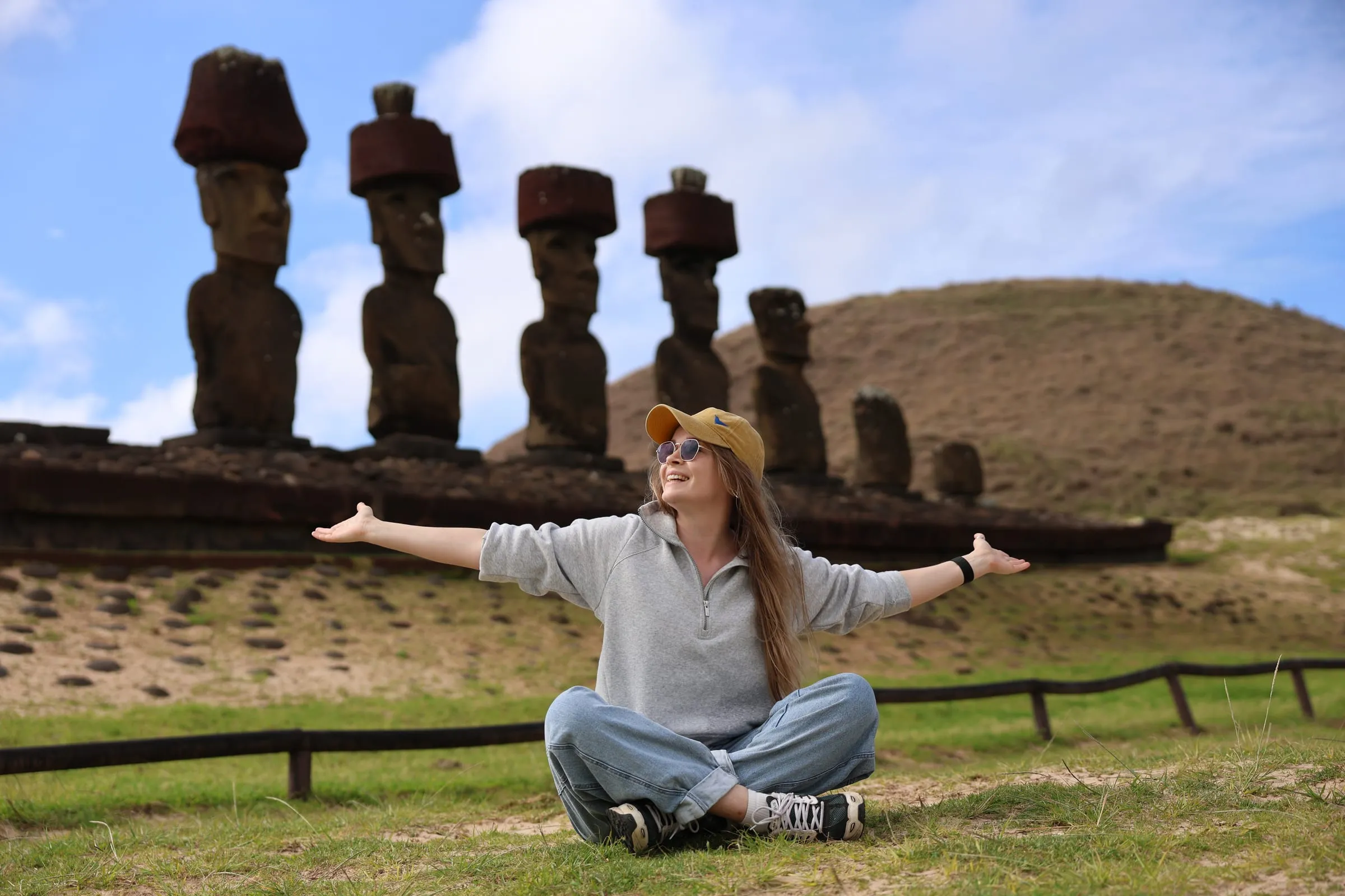 Liubov sitting with her arms open in front of the moai statues on Easter Island