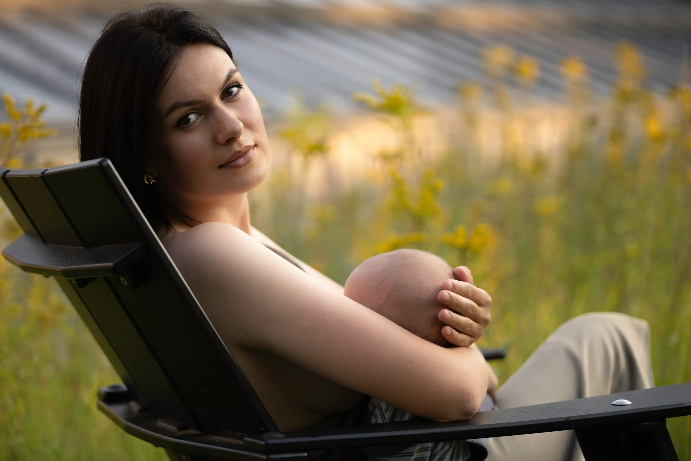 Mother relaxing in a chair with her baby at sunset