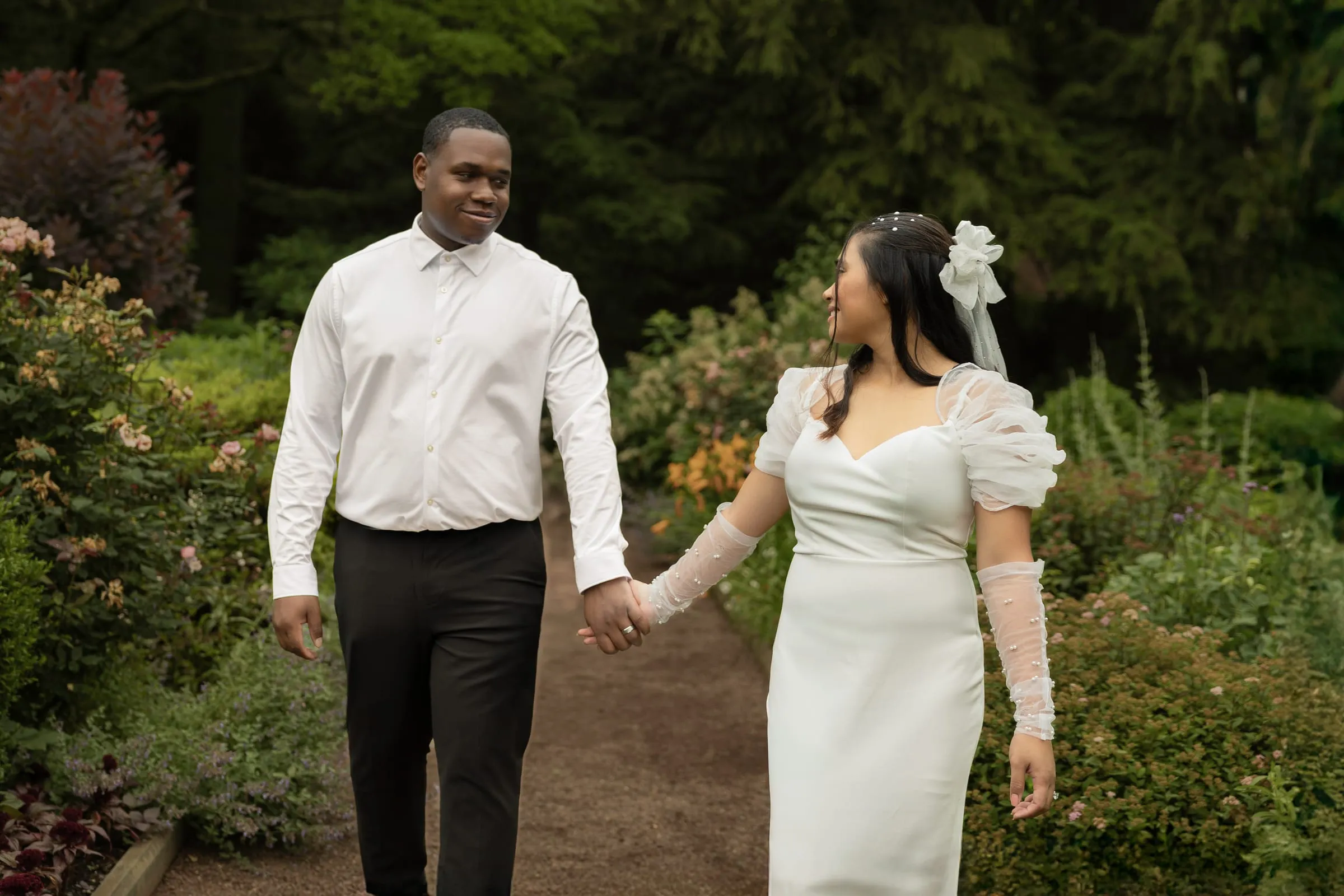 Couple walking hand in hand along a garden path