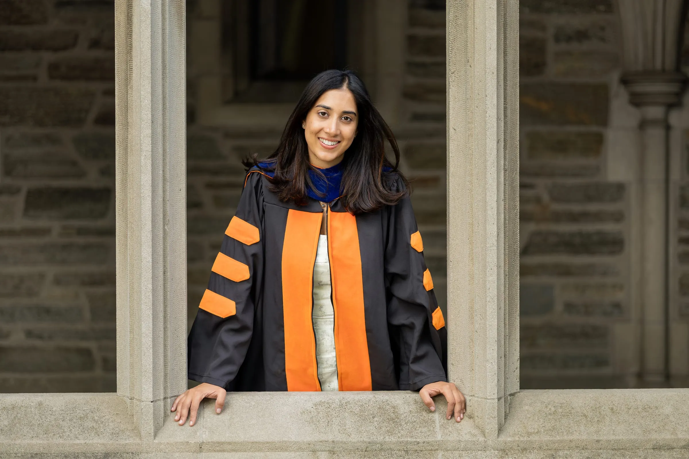 Graduate in a doctoral gown leaning out of a stone window frame